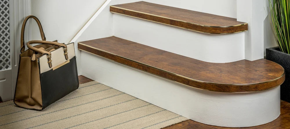 Wood-effect flexible stair nosing installed on curved and straight steps, enhancing traditional interiors by Premier Trims.