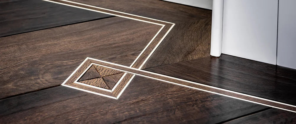 Custom-designed Premier LVT Floor Inlays by Arra Flooring installed in dark wood flooring with chrome decorative trims for luxury interiors.