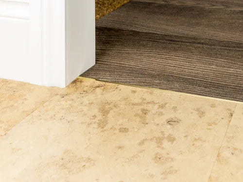 Low-profile solid brass transition strip connecting tile to wood flooring for smooth, durable floor transitions.