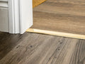 Solid brass transition strip bridging two wood floor types, ensuring a smooth and professional flooring finish.