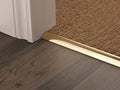 Solid brass flooring transition strip between dark wood and loop carpet, ensuring a flush and elegant floor junction.
