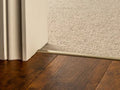 Brass flooring transition strip connecting dark wood and light carpet, ideal for doorways and room transitions.
