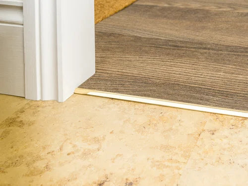 Solid brass transition strip joining tile to wood flooring for a seamless finish in doorway. Ideal for hard floor to carpet transitions.