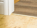 Solid brass transition strip joining tile to wood flooring for a seamless finish in doorway. Ideal for hard floor to carpet transitions.