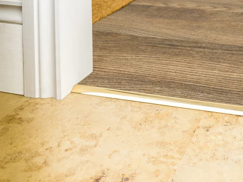 Solid brass trim strip used to transition between tile and wood flooring, offering a smooth and refined floor edge.