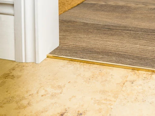 Solid brass transition strip joining tile to wood flooring for a seamless finish in doorway. Ideal for hard floor to carpet transitions.