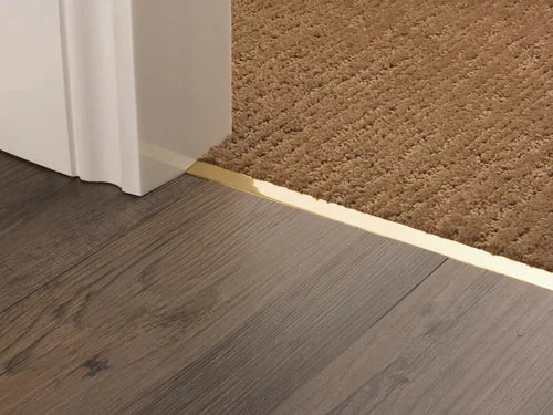 Brass transition strip joining laminate wood and carpet flooring, providing a sleek and seamless doorway finish.