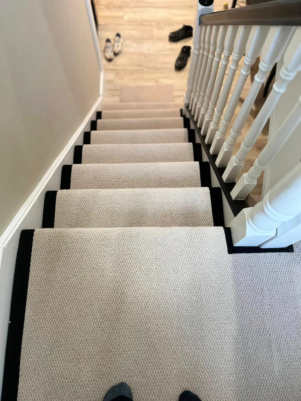 Completed neutral stair runner installation with dark edging